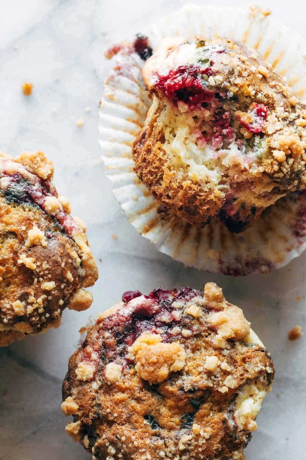 Triple Berry Cheesecake Muffins fresh out of the oven, topped with berries.