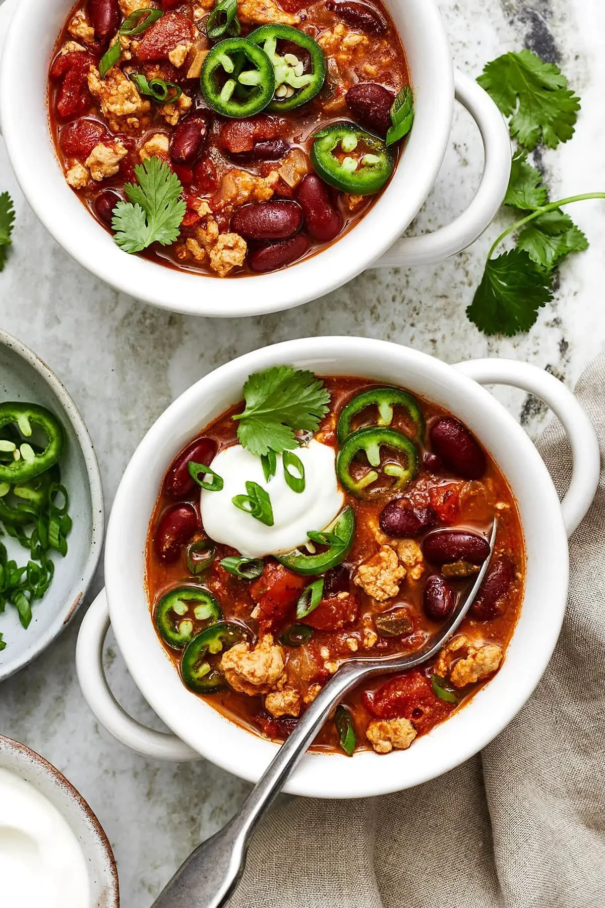 A bowl of hearty turkey chili with beans and spices garnished with fresh herbs