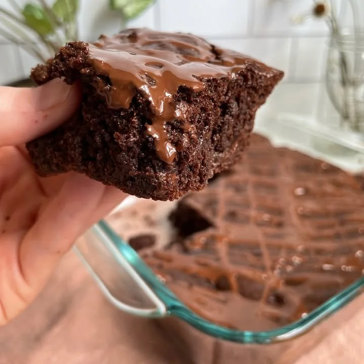 Delicious grain-free tahini brownies on a wooden plate with chocolate drizzle
